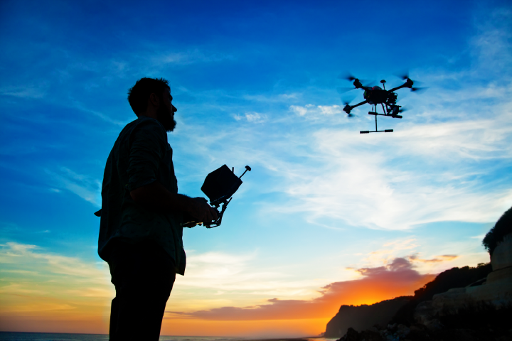 Man controlling a drone outside at sunset